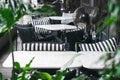 A welcoming outdoor marble tables and chairs with cozy black and white pillows surrounded by  bright green plants on terrace in Royalty Free Stock Photo