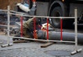 A welder behind a plastic barrier works with an old pipe repairing a heating main