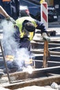 Welder construction worker working on city street crossroad, replacing old rotten tram rails with new once and arc welding them Royalty Free Stock Photo