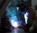 Welder at the factory in a welding mask welds metal parts, welding and sparks, tool
