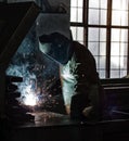 Welder at the factory welds metal parts, welding and sparks, dirty production, harmfulness