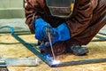 A welder makes a frame from a profile pipe by connecting them with electric welding Royalty Free Stock Photo