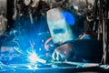 Welder man in a protective mask of iron is engaged in the process of welding and metal work in the workshop of an industrial plant Royalty Free Stock Photo