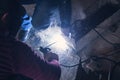 Welder performs welding work on metal in protective mask