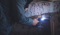 Welder performs welding work on metal in protective mask