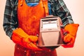 Welder in protective suit, gloves, holding a welding mask, Close-up, Fiery colors