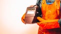 A welder in a protective suit, wearing gloves, holding a welding mask under his arm. Close-up, Space for text, Fiery Colors