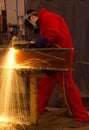 Welder in red overalls cuts metal. Royalty Free Stock Photo