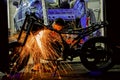 Welder repairs a motorcycle in a garage. Silhouette of a worker with a beam of sparks.