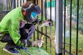 A welder wearing protective clothing, helmet and gloves welds a metal fence around the work area