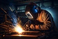 Welder welding metal with argon arc welding machine and has welding sparks. A man wears welding mask and protective gloves. Safety