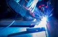 Welder welding metal with argon arc welding machine and has welding sparks. A man wears protective gloves. Safety in industrial