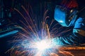 Welder welding metal construction on factory. Long traces of sparks
