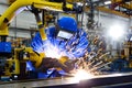 Welder welding metal in a factory with help of robotics