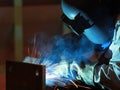 Welder is welding steel structure with all safety equipment in factory