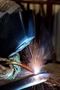 A welder using a wire feed welder to join two pieces of metal together.