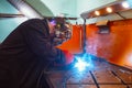 A welder welds metal into his workshop. Blue welding sparks. Gas combustion and blue smoke. Small welding workshop Royalty Free Stock Photo