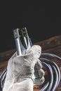 A welder in white welding gloves holds a wire with a ground terminal in his hand. Studio photo in hard light