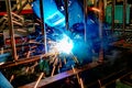 A welder at work in a workshop produces metal structures. Sparks from welding fly around Royalty Free Stock Photo