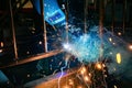 A welder at work in a workshop produces metal structures. Sparks from welding fly around Royalty Free Stock Photo