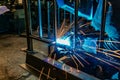 A welder at work in a workshop produces metal structures. Sparks from welding fly around Royalty Free Stock Photo