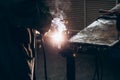Welder works at workbench in welding shop. Flash. Electric arc. Dark photo. Background