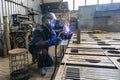 A welder in a workshop manufactures and connects metal structures, a worker in a protective mask performs welding work