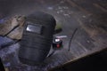 Welding Mask and tool with leather gloves, tape measur on wooden table, accessories for arc welding