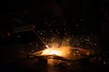 Welding, metal working on dark background, with golden bokeh and flare of sparks. Technician workshop, manufacturing industry