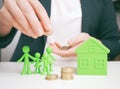 Welfare benefits koncept. Hands of woman making a gesture of protection over family and home with piggy bank. House construction Royalty Free Stock Photo