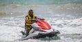 Weligama, Sri Lanka - 10 29 2022: Handsome Jetsky rider with a yellow jacket driving a jetski on a sunny day