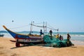 Group local of fishermen reviewing and folding fishing nets near the traditional wooden boat