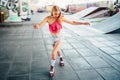 Well-built and slim girl is posing on camera. She is looking down to her knees and rollerblading. She is doing that very Royalty Free Stock Photo