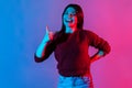 Well done, good job! Neon light portrait of joyful brunette woman showing thumbs up, like gesture to camera Royalty Free Stock Photo