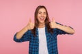 Well done! Portrait of enthusiastic girl in checkered shirt standing with double thumbs up and smiling broadly