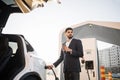 Arabian man drinking coffee while charging car Royalty Free Stock Photo