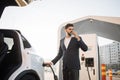 Arabian man drinking coffee while charging car Royalty Free Stock Photo