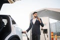 Arabian man drinking coffee while charging car Royalty Free Stock Photo