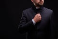 Handsome young priest with bread posing on a black background.