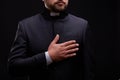 Handsome young priest with bread posing on a black background.