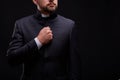 Handsome young priest with bread posing on a black background.