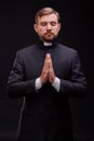 Handsome young priest with bread posing on a black background.