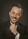 Well-dressed businessman toothy smiles while touching his chin with his hand. Portrait of handsome caucasian man in