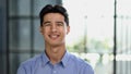 Well dressed young Asian businessman smiling confidently while standing alone in a bright modern office Royalty Free Stock Photo