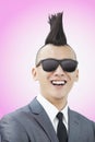 Well-dressed young man with Mohawk and sunglasses smiling, pink background Royalty Free Stock Photo