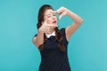 Well dressed young woman showing frame sign and wink.