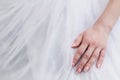 Well-groomed hand of the bride with a beautiful manicure on a white wedding dress Royalty Free Stock Photo