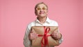 Pretty excited elderly blonde woman of 60-70 years holding gift-wrapped box
