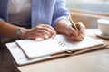 Well groomed woman hand holding gold pen and writing notes with gold pen in notebook beside window. Royalty Free Stock Photo