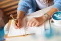 Well groomed woman hand holding gold pen and writing notes with gold pen in notebook. cup of hot butterfly pea latte or Royalty Free Stock Photo